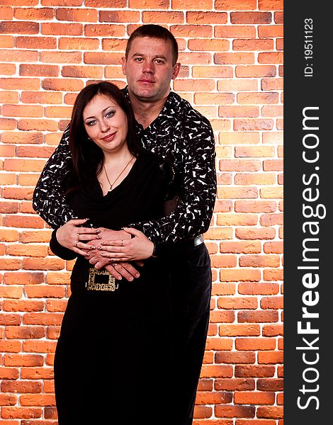 Happy couple standing against brick wall background