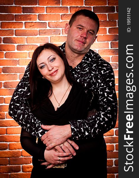 Happy couple standing against brick wall background