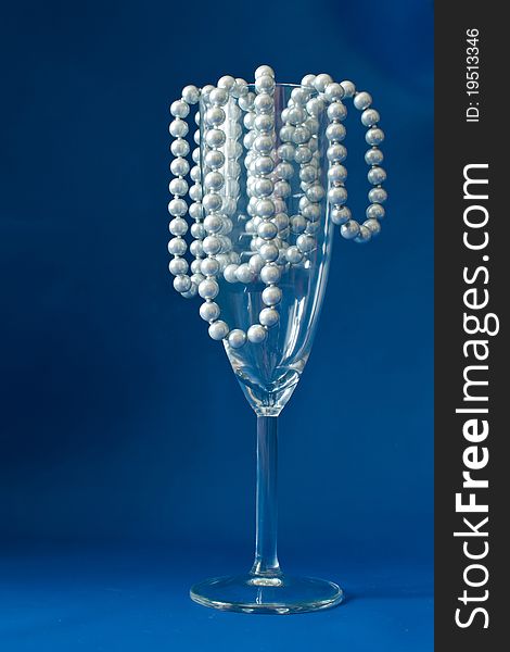 Wine glass on a dark blue background with a beads. Wine glass on a dark blue background with a beads