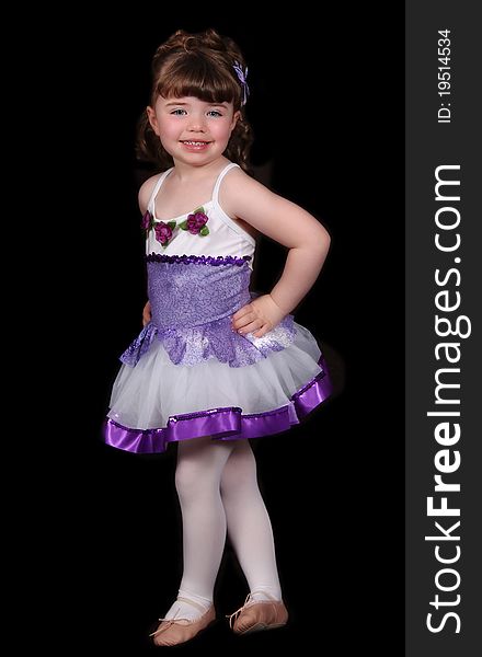 Adorable little girl in purple and white ballet costume standing and posing proudly. isolated on black. Adorable little girl in purple and white ballet costume standing and posing proudly. isolated on black