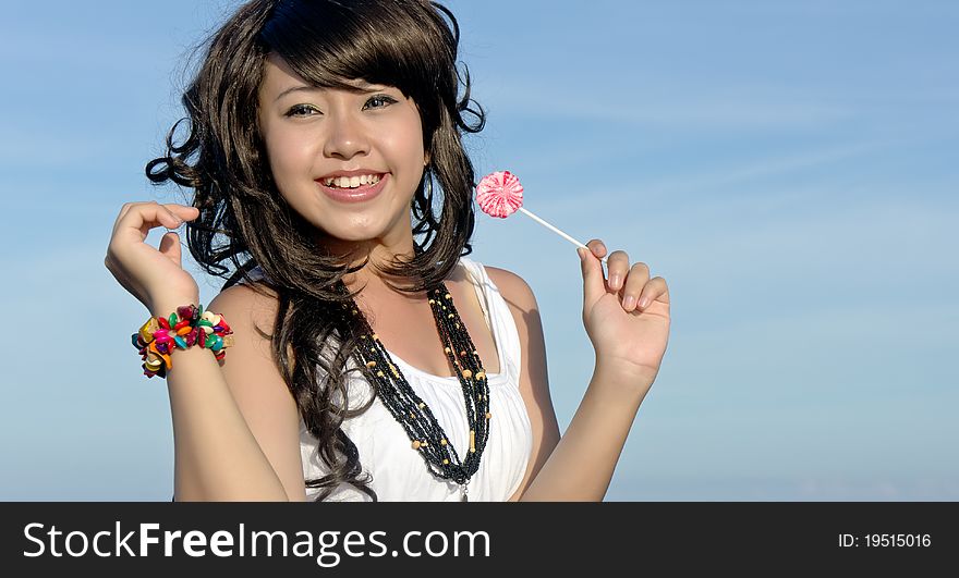 Young pretty asian girl enjoys eating candy