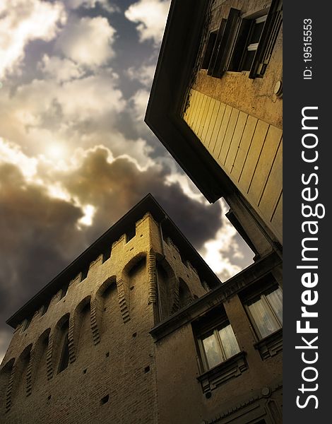 Exterior of an anicent building in Parma of Northern Italy with dramatic cloudscape and breaking sun behind