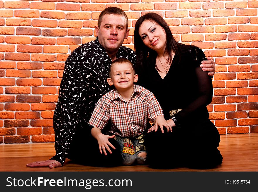 Happy family sitting against brick wall