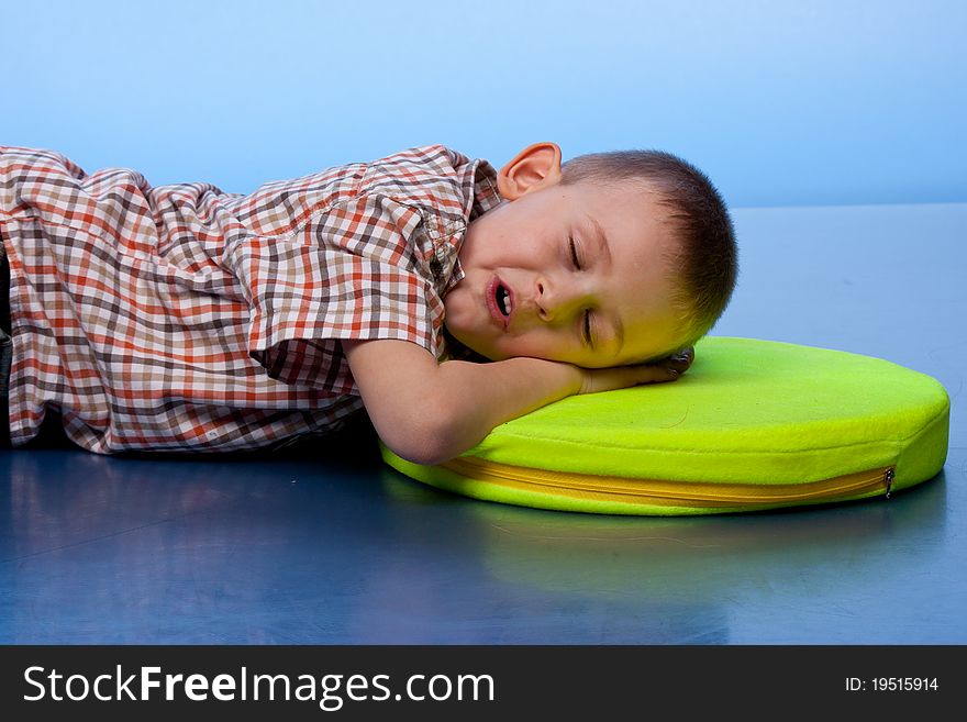 Cute boy sleeping on a pillow against blue background