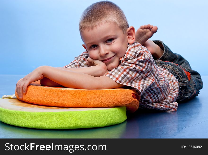 Cute boy resting on a pillow against blue background