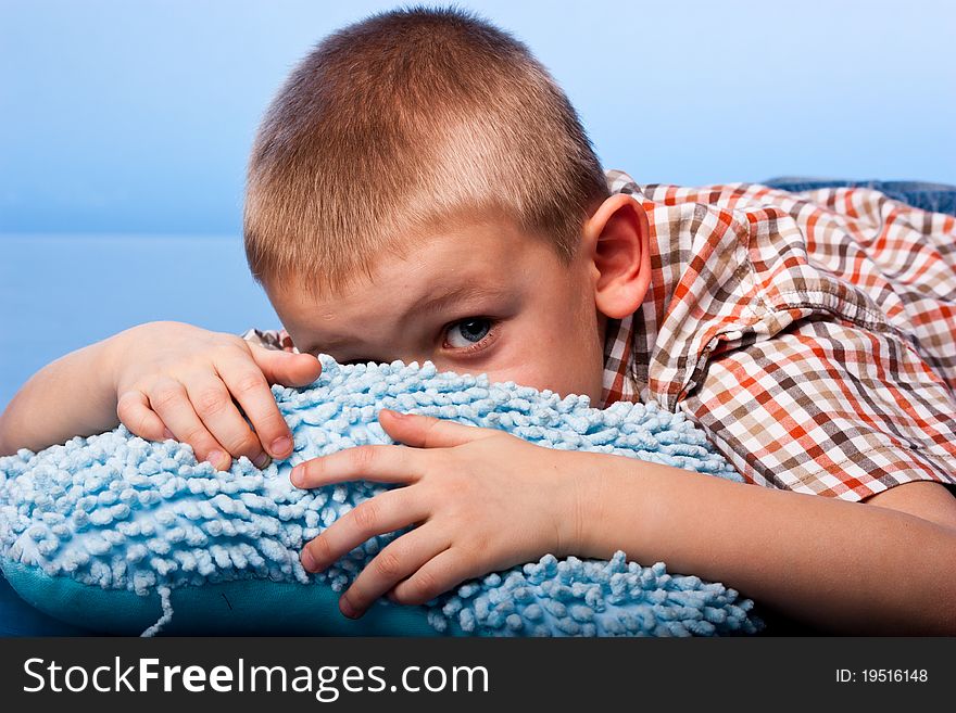 Cute boy resting on a pillow against blue background