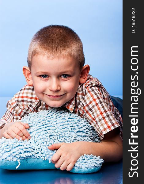 Cute boy resting on a pillow against blue background