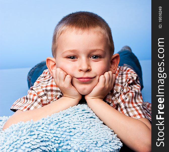 Cute boy resting on a pillow against blue background