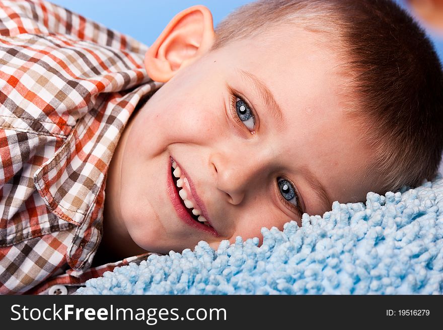 Cute boy resting on a pillow against blue background