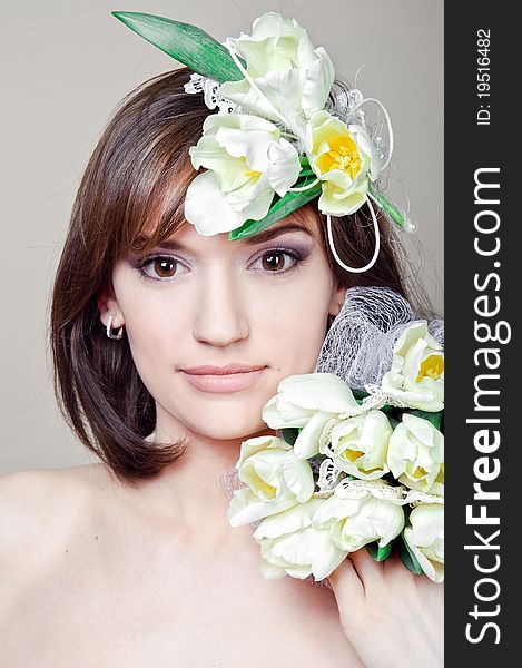 The beautiful girl holds white flowers on a gray background. The beautiful girl holds white flowers on a gray background