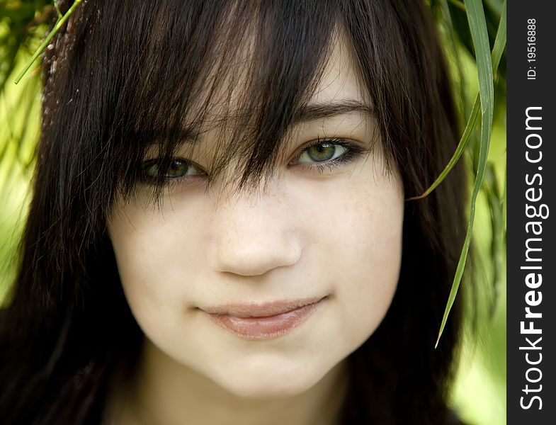 Portrait of brunette teen girl at green outdoor.