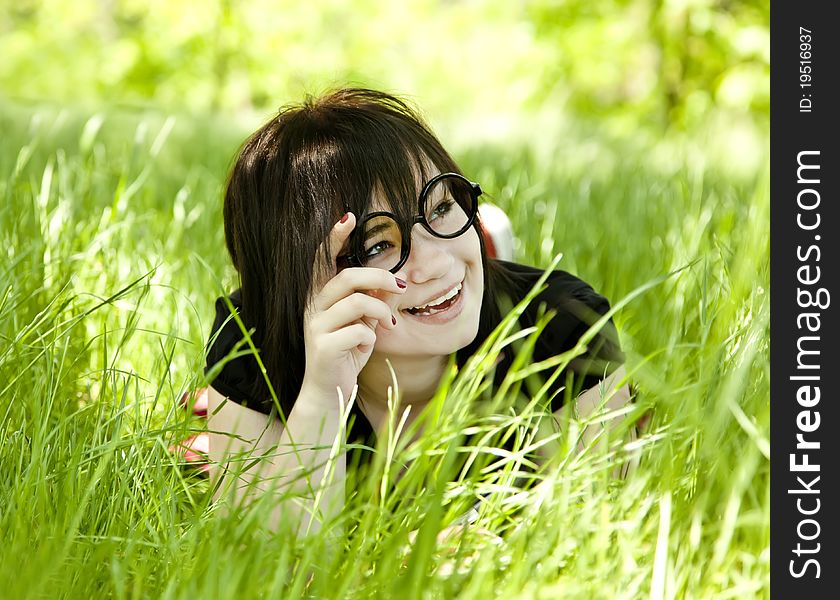 Young teen girl in glasses at green grass.