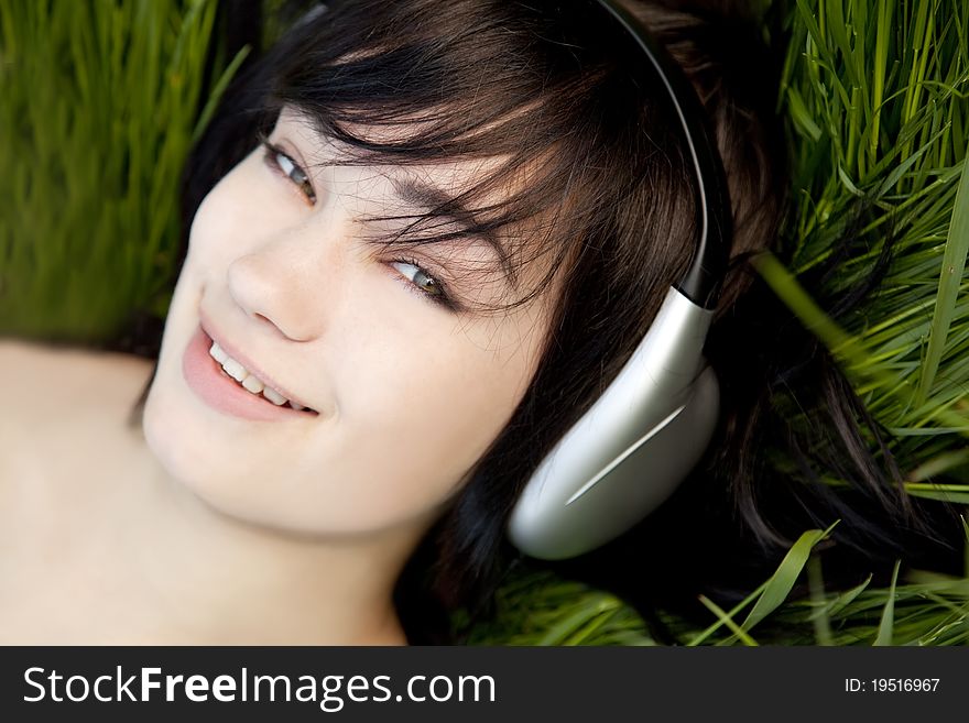 Brunette Girl Listening Music At Green Grass