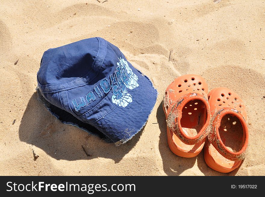 Kid's thongs and a sun cap at the beach. Kid's thongs and a sun cap at the beach