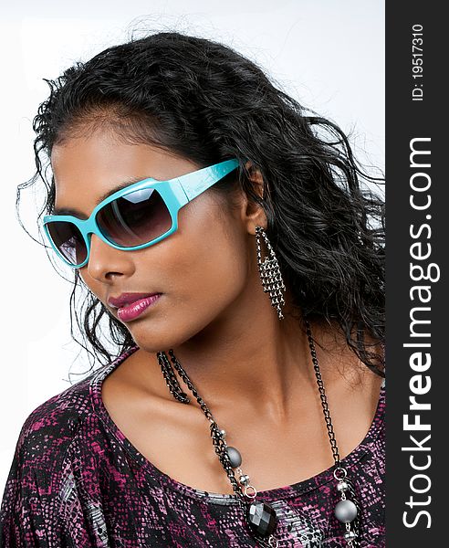 Beautiful woman of east indian ancestry with wide neck dress top looking downward sporting large blue sunglasses. Beautiful woman of east indian ancestry with wide neck dress top looking downward sporting large blue sunglasses