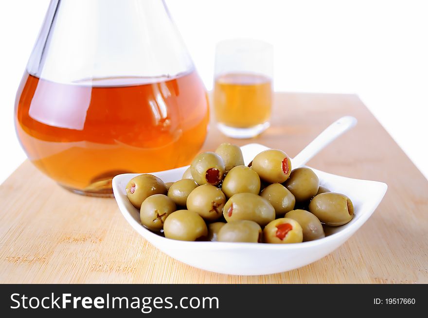 Olives with red peppers and schnapps bottle on wooden bamboo plate. Olives with red peppers and schnapps bottle on wooden bamboo plate