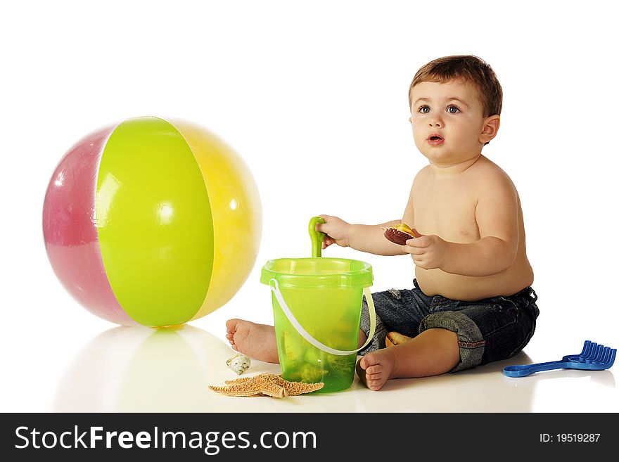 A shirtless baby boy in rolled up jeans with a beach ball and sandpail full of ocean shells. Isolated on white. A shirtless baby boy in rolled up jeans with a beach ball and sandpail full of ocean shells. Isolated on white.