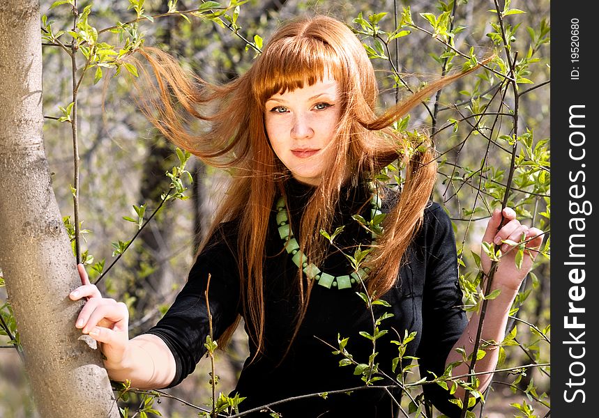 Portrait of the young woman with developing hair in a spring garden