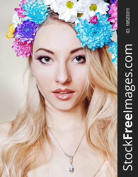 Beautiful young woman with colorful flowers in hair
