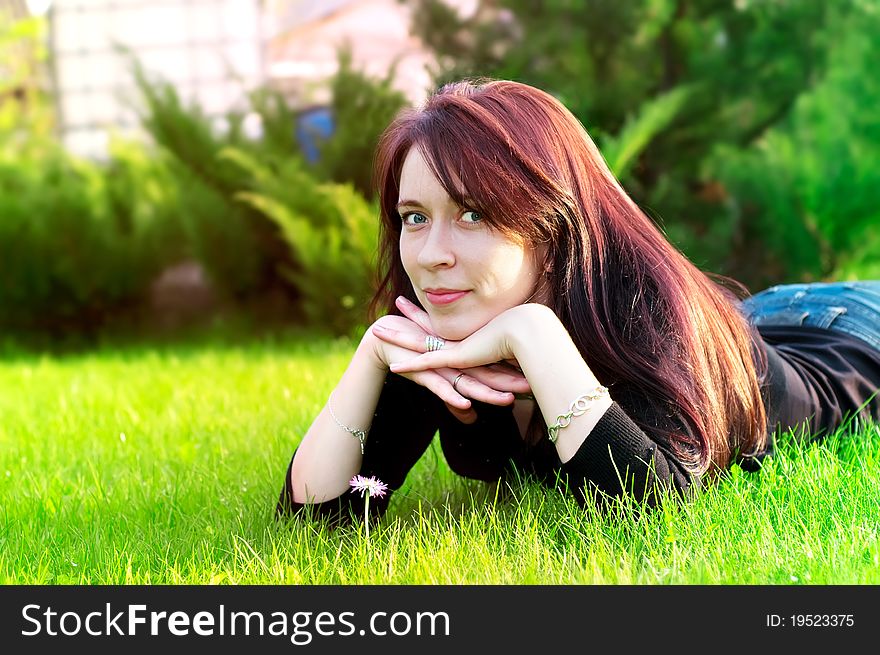 Potrait of a young pretty woman lying on green grass in the meadow