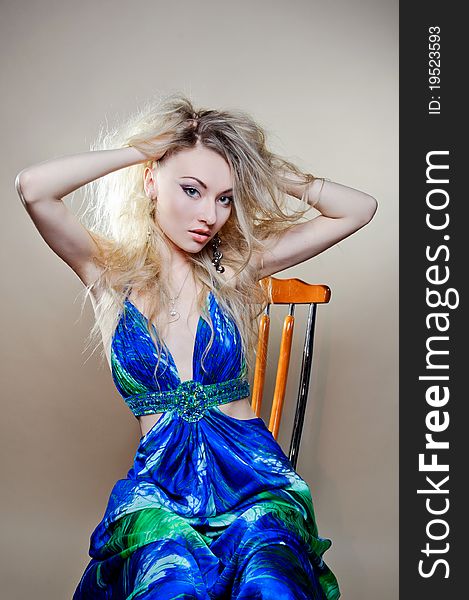 A beautiful young woman sitting on a chair in a blue dress