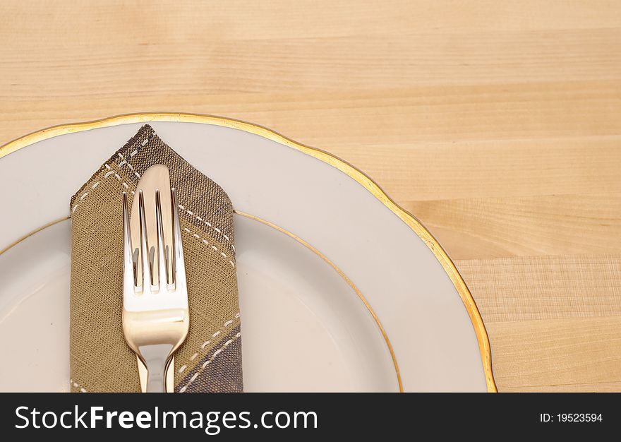 Knife and fork with white plate on wooden table