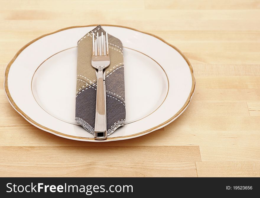 Knife and fork with white plate on wooden table