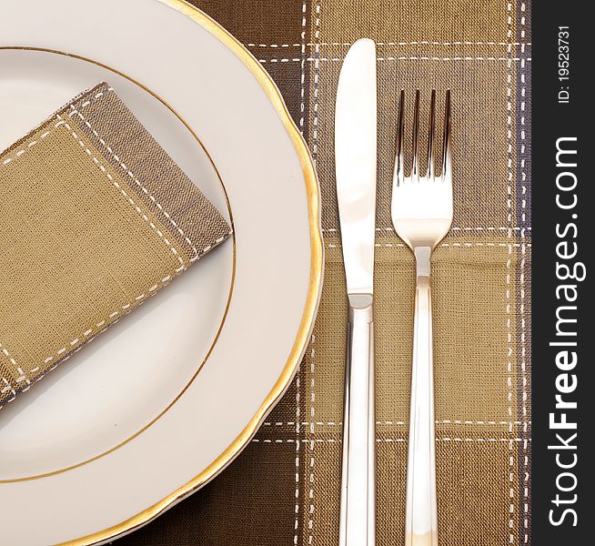 Knife and fork with white plate on wooden table