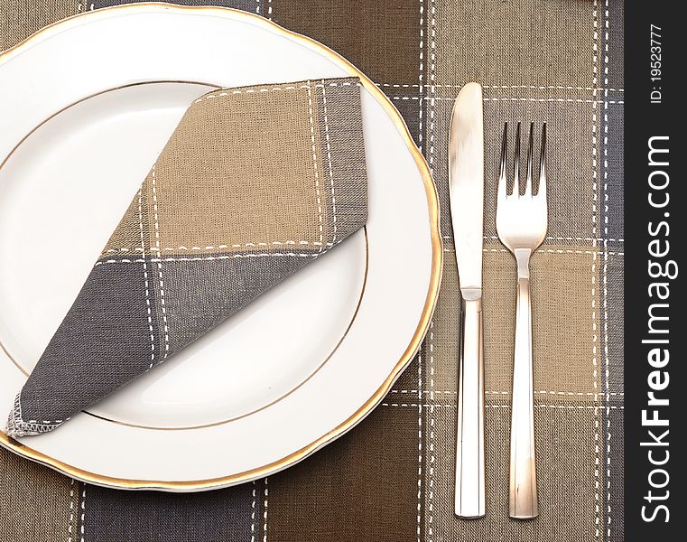 Knife and fork with white plate on wooden table