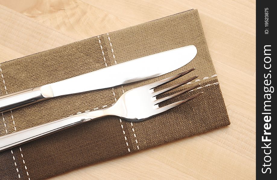 Knife and fork with napkin on wooden table