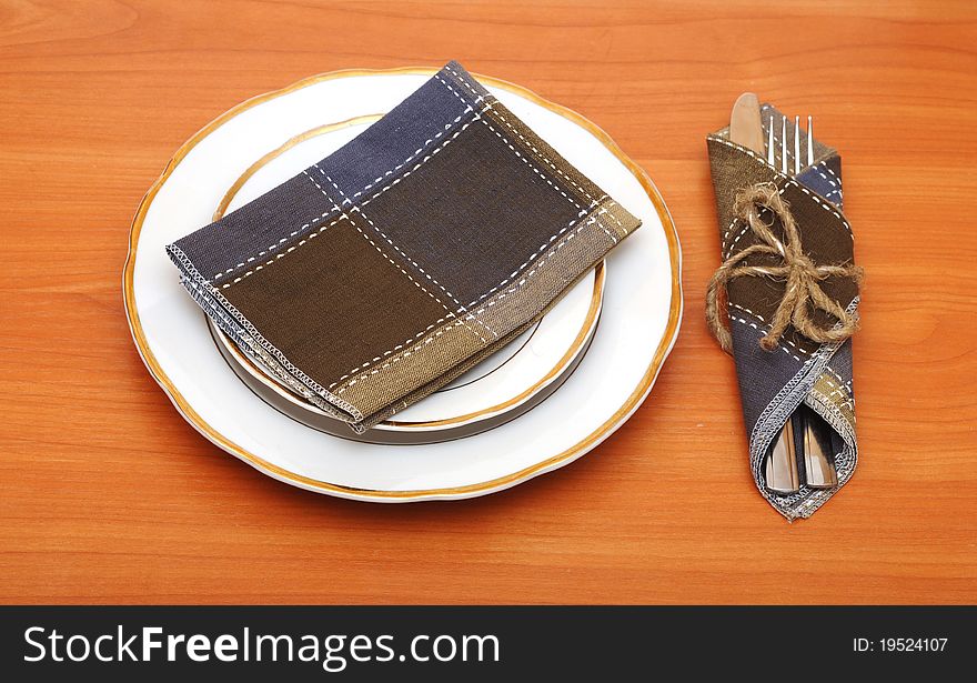 Knife and fork in textile napkin on wooden table