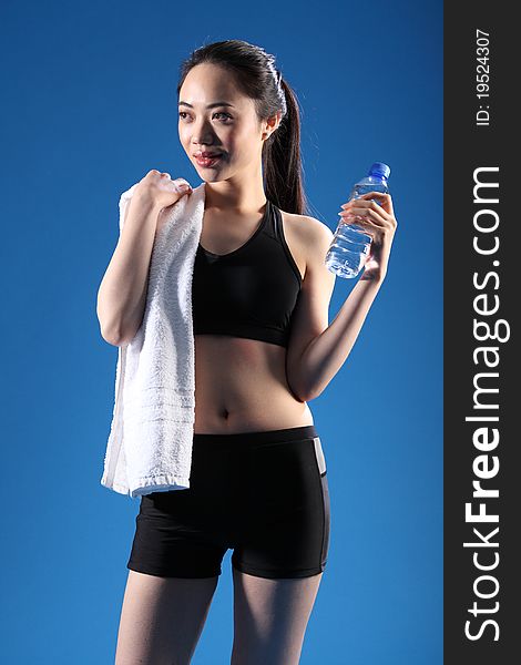 Happy and relaxed after a fitness workout, a beautiful Chinese Asian girl wearing a black sports outfit, standing with bottled water and a towel. Happy and relaxed after a fitness workout, a beautiful Chinese Asian girl wearing a black sports outfit, standing with bottled water and a towel.