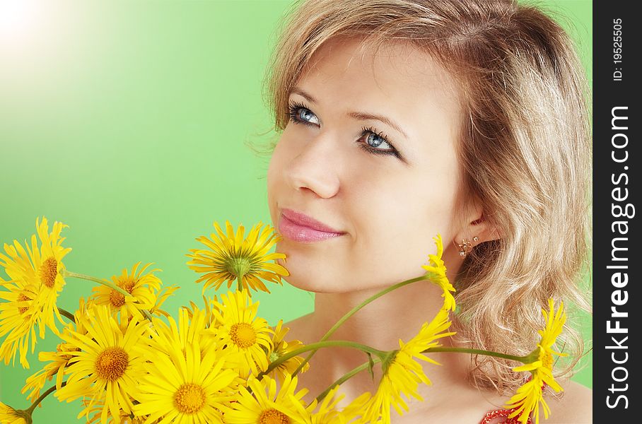 Beautiful blond with the yellow flowers against the green background