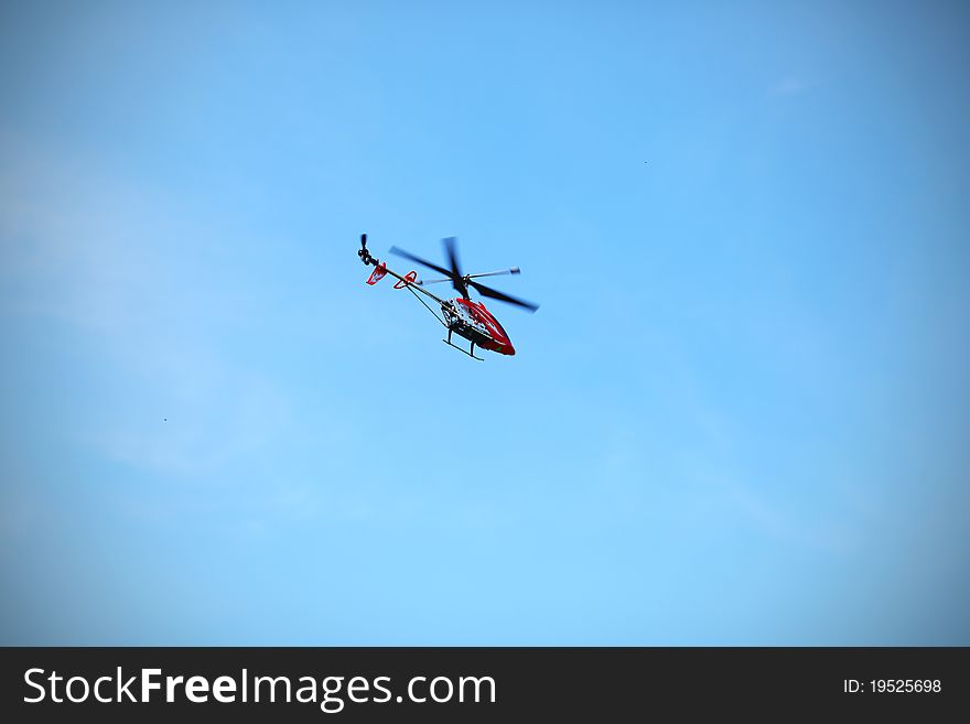 Radio controlled helicopter flying against blue sky.
