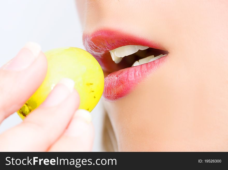 Young woman with grape in her mouth