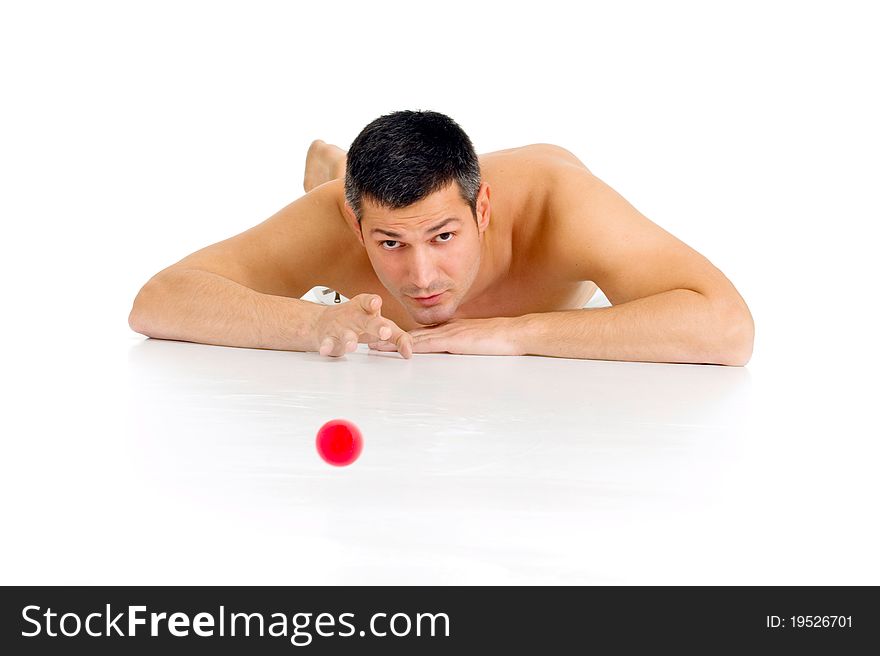 Bare-chested man lying on the floor playing with marble in white background