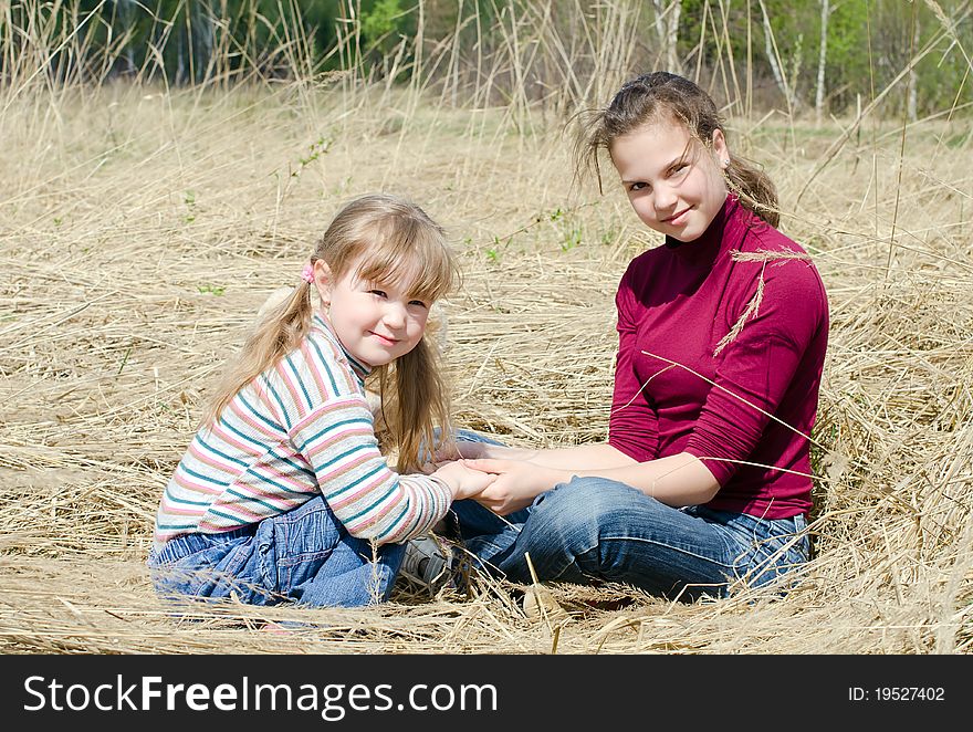 Two beautiful girls on a dry grass