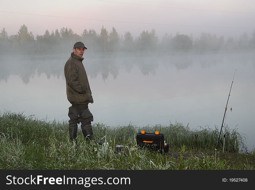 Fisherman on a morning foggy lake