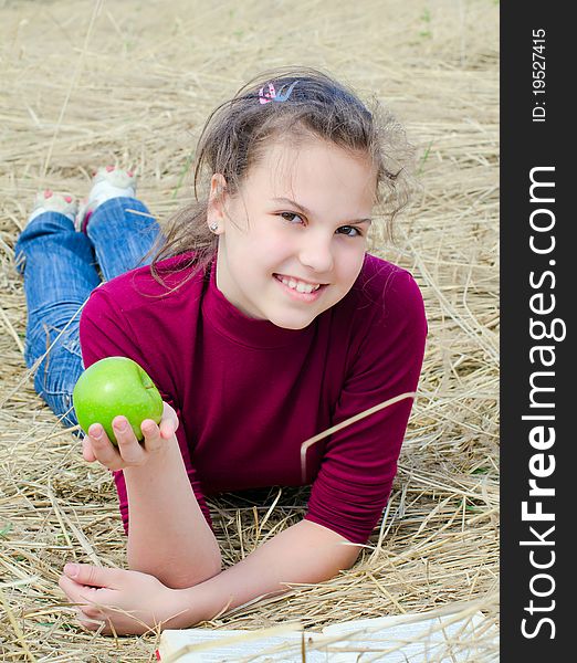 Girl with an apple on dry  grass