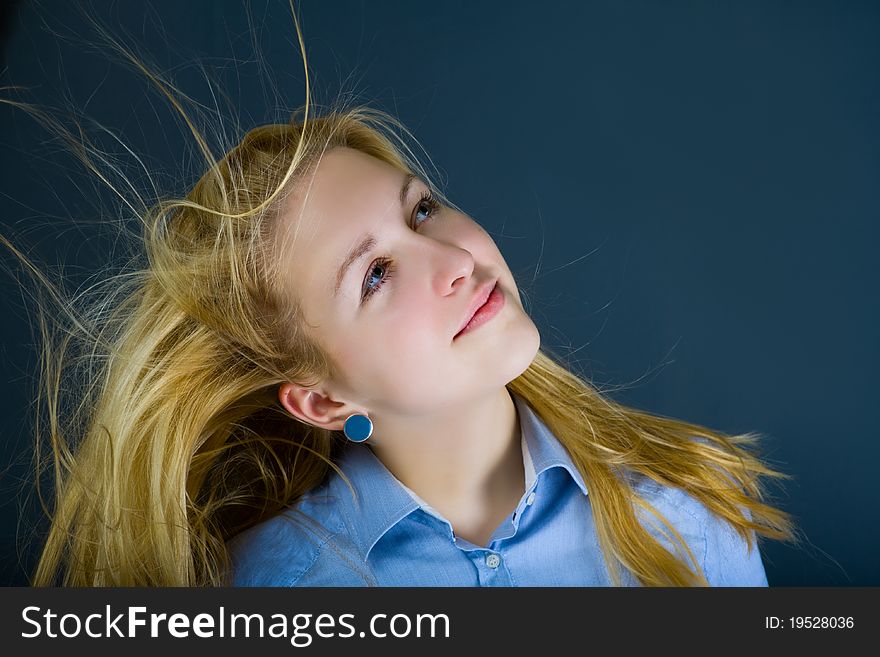 Young teenage girl with flying in the wind blond hair dreamily looking up. Young teenage girl with flying in the wind blond hair dreamily looking up