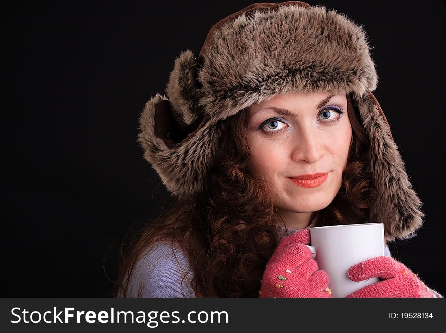 Romantic image of beautiful woman in a fur hat with a cup