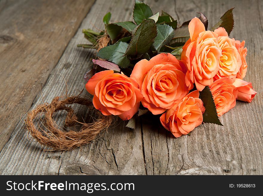 Bunch of orange roses on old wooden table