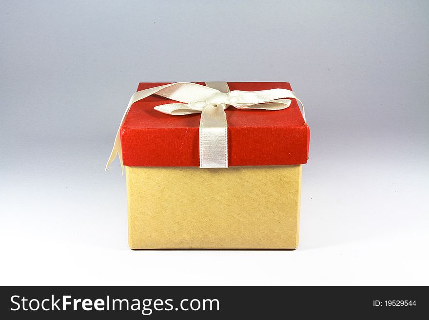 Single red gift box with white ribbon on white background.