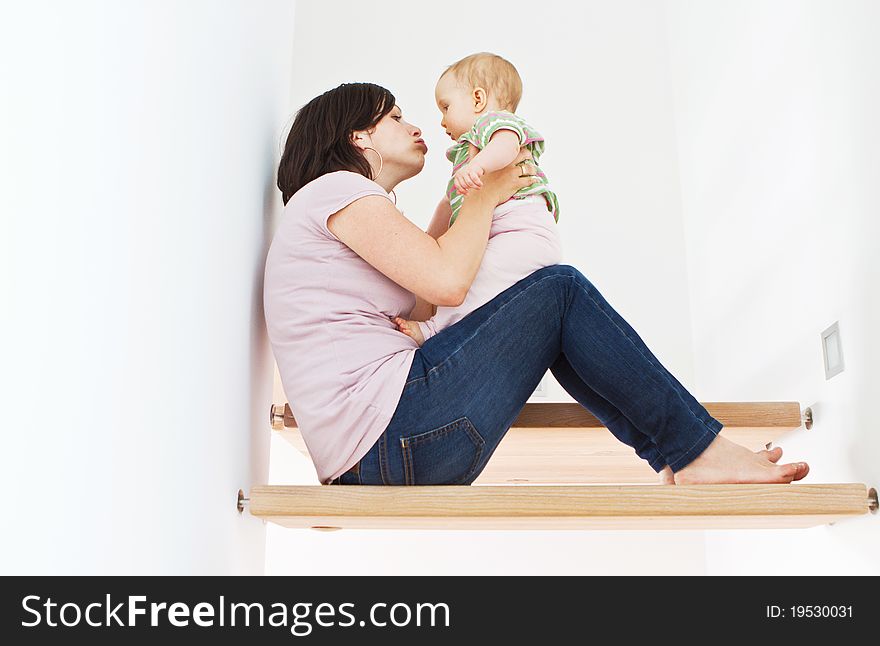 Young mother at home with her little baby on stairs. Young mother at home with her little baby on stairs.