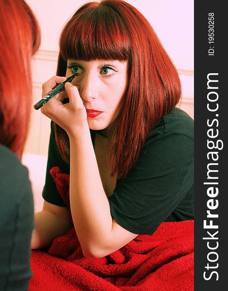 Young brunette applying make-up in mirror