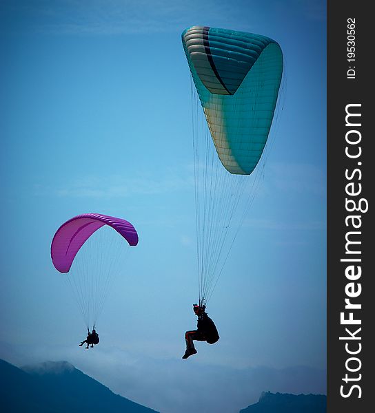 Two paragliders soaring in a blue sky