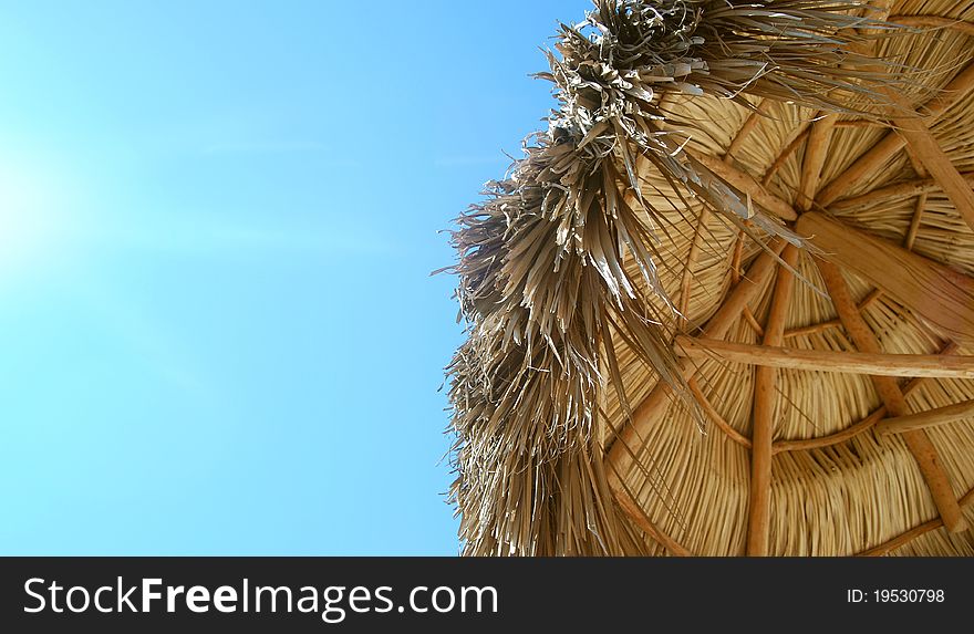 A point of view in a tropical beach, palm umbrella and blue sky. A point of view in a tropical beach, palm umbrella and blue sky