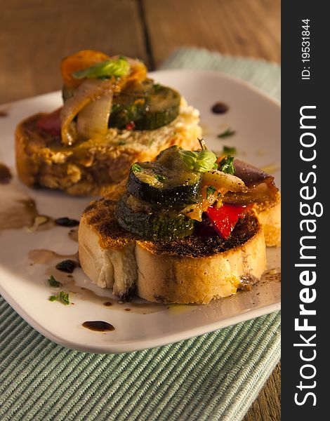 Roasted Mediterranean vegetables on a rustic piece of toast on a wooden table. Roasted Mediterranean vegetables on a rustic piece of toast on a wooden table.