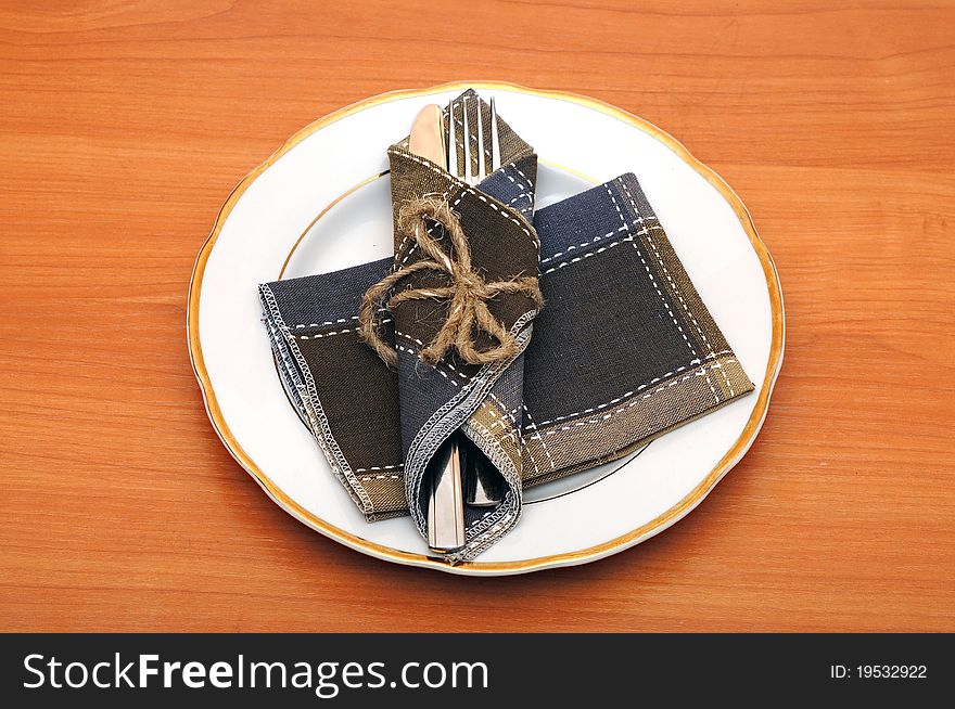 Knife and fork in textile napkin on wooden table