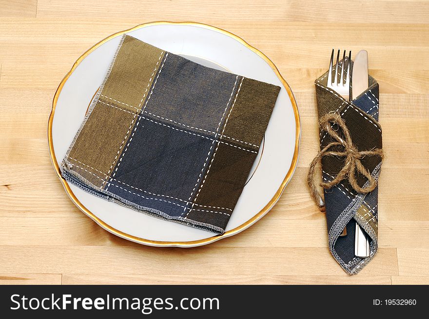 Knife and fork in textile napkin on wooden table